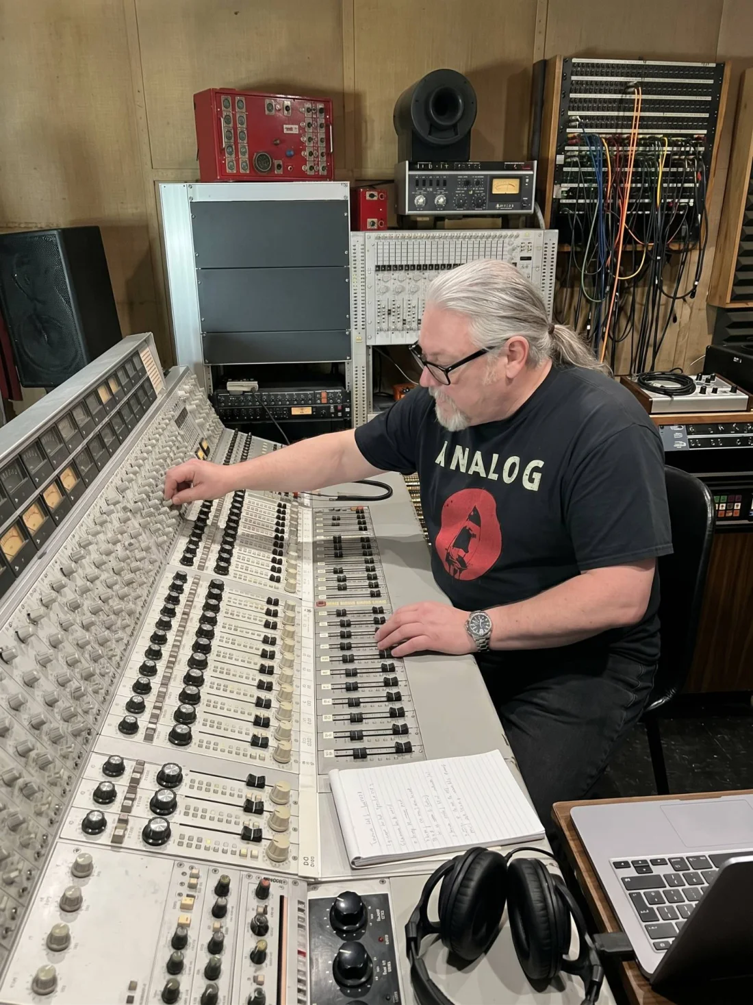 Jonny Reckless at a large analogue mixing console in a recording studio, in an ANALOG T-shirt.