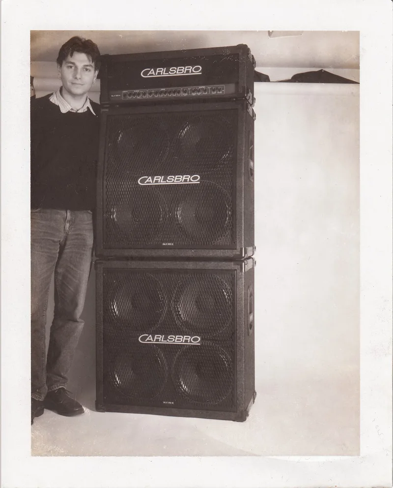 A young Jonny Reckless standing beside a Carlsbro GLX guitar amplifier stack.